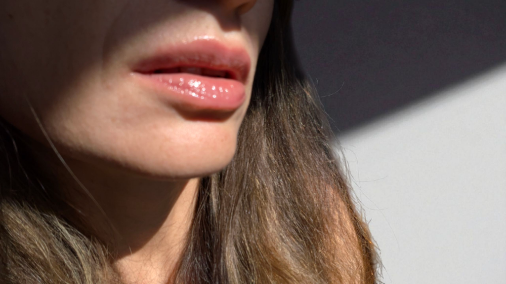 Close-up of lips wearing AXIS-Y Vita Glow Lip Oil in Chilled Berry, showing a glossy, natural, non-sticky finish under soft daylight.
