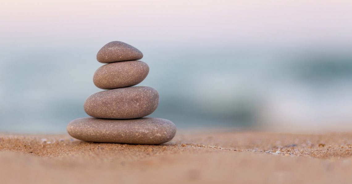 Stacked stones on a sandy beach symbolizing harmony and inner balance