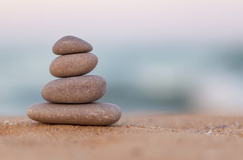Stacked stones on a sandy beach symbolizing harmony and inner balance